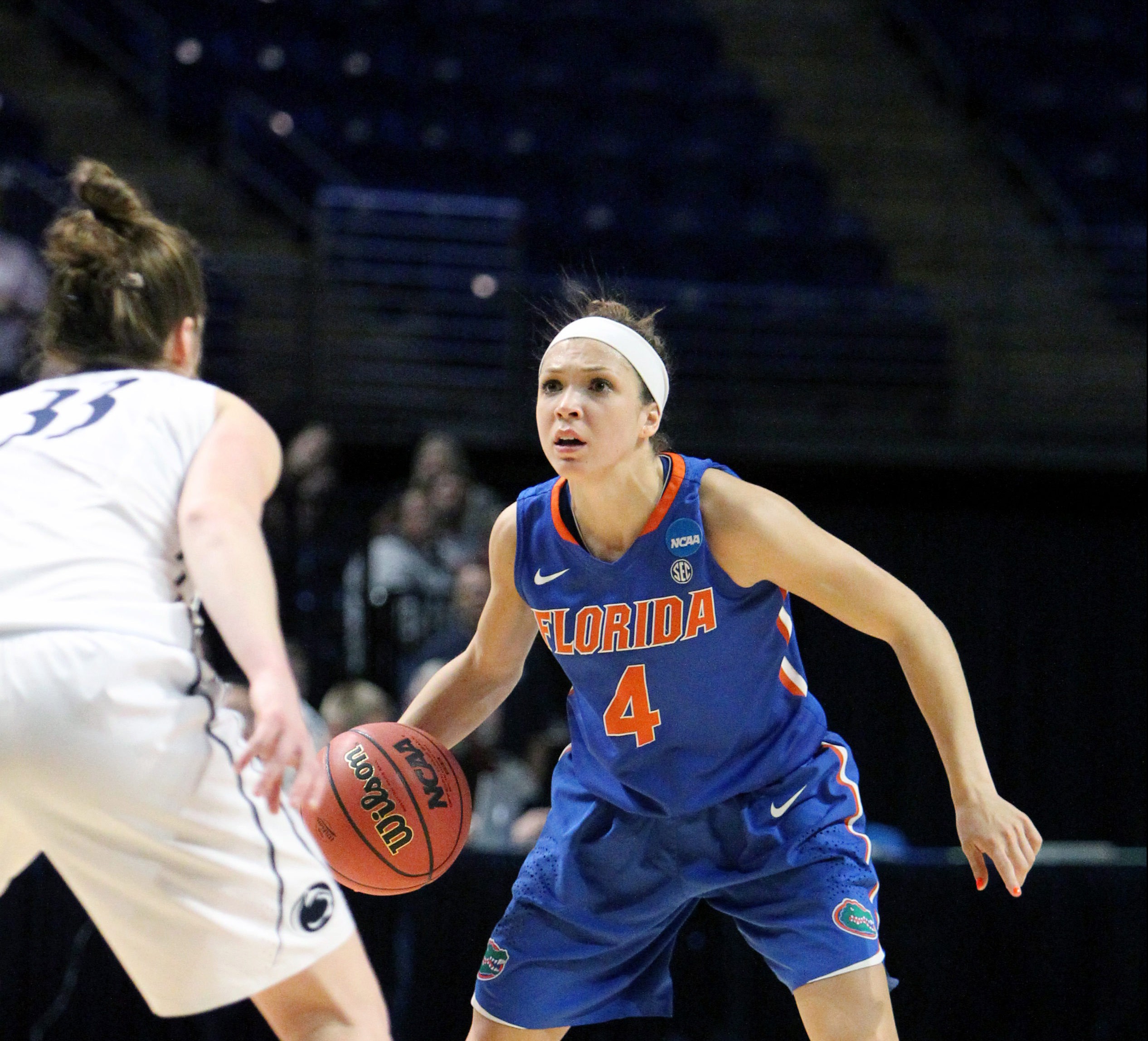 Florida women's basketball player #4 dribbles while defended by opponent in white jersey during NCAA game.