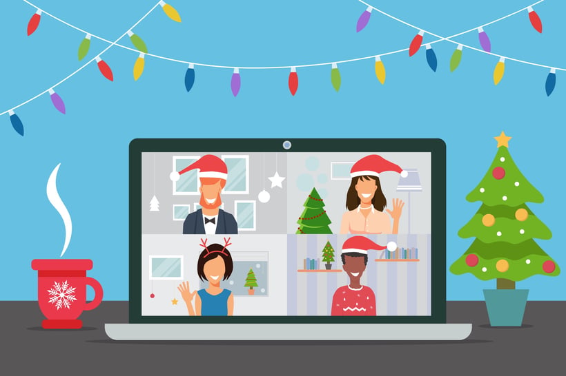 Four people in festive holiday attire join a virtual video call on a laptop, surrounded by Christmas lights, tree, and hot cocoa.