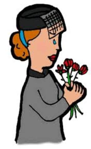 Grieving woman in black veil holding red tulips, tear on cheek, solemn expression.