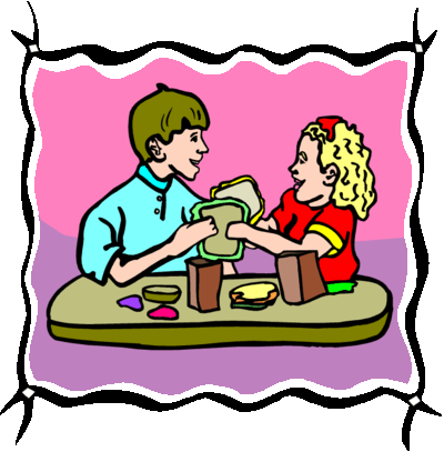 Two children smiling while sharing sandwiches and snacks at a table.
