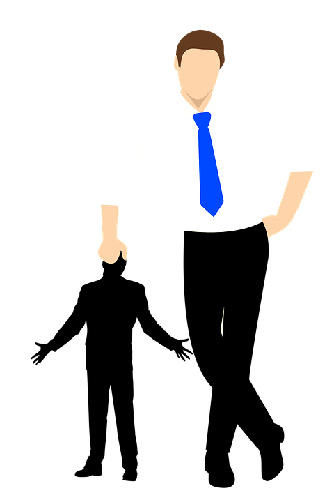 Businessman in white shirt and blue tie standing confidently with hands on hips.