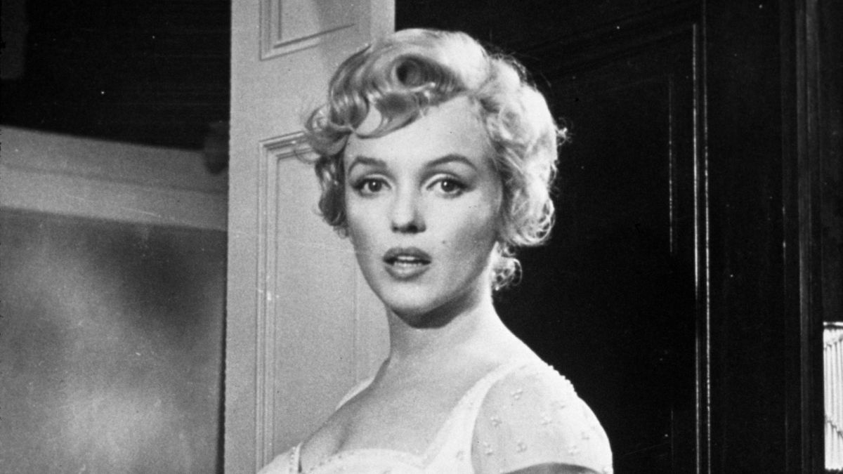 Marilyn Monroe in a white dress, looking over her shoulder with a surprised expression, black-and-white film still.