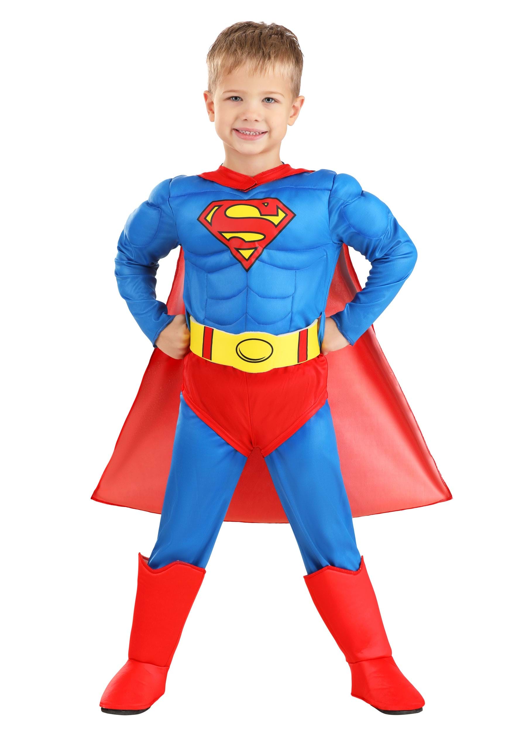Young boy wearing a classic Superman costume with padded muscles, red cape, and boots, posing confidently.
