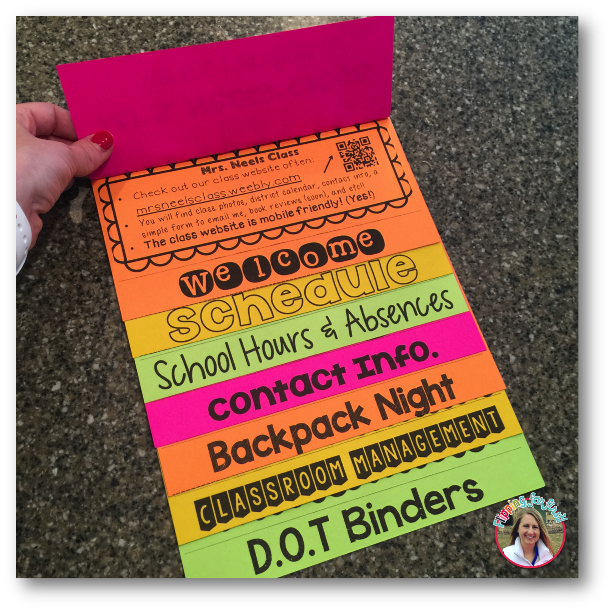 Colorful accordion-style classroom information brochure held open by a hand with red nail polish.