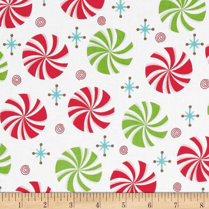 Festive red and green peppermint swirl pattern with blue stars and brown spirals on white background, fabric swatch with ruler.