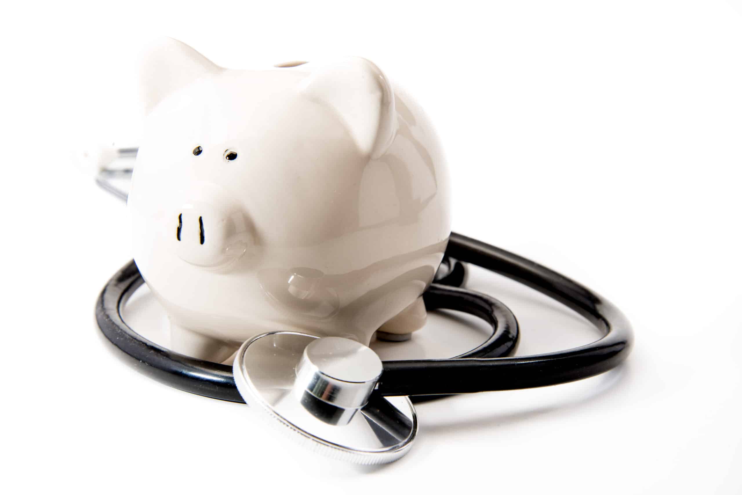 White ceramic piggy bank wrapped with a black stethoscope on a white background.