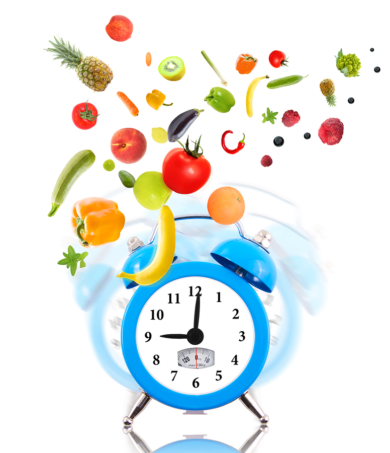 Blue alarm clock with fresh fruits and vegetables bursting out, symbolizing healthy eating and timely nutrition.