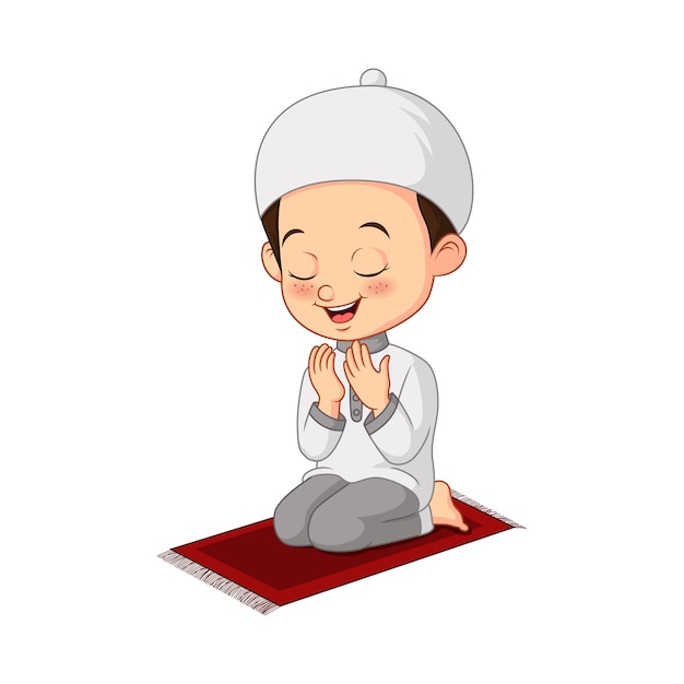 A smiling Muslim boy in white thobe and kufi cap praying on a red prayer mat with hands raised.