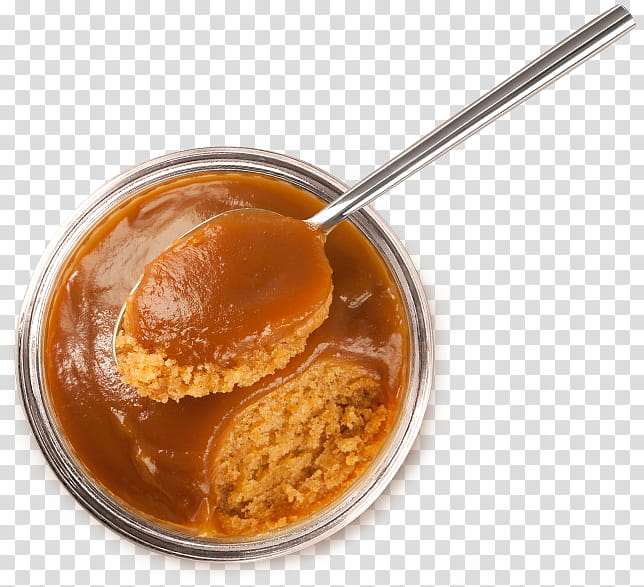 A spoon lifting a scoop of rich, glossy caramel sauce from a glass jar, with crumbly shortbread biscuit pieces submerged inside.