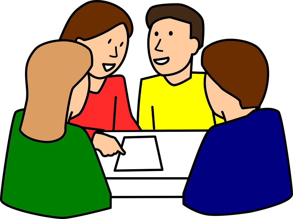 Four diverse people collaborating around a table with documents and discussion.
