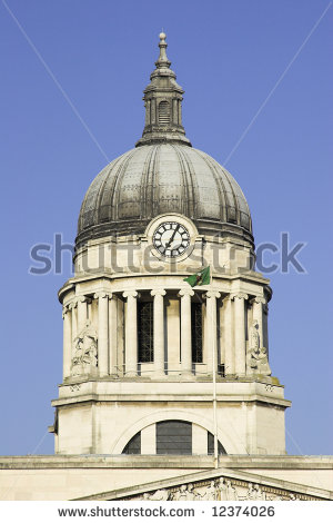 Historic clock tower with domed roof, classical columns, and Irish flag against a clear blue sky.