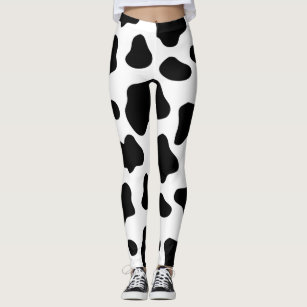 Person wearing black-and-white cow print leggings with sneakers, full-length front view.