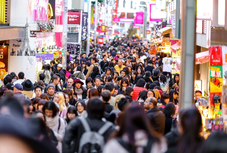 Crowded street in Tokyo’s Shibuya district at dusk, with neon signs, shoppers, and vibrant urban energy.