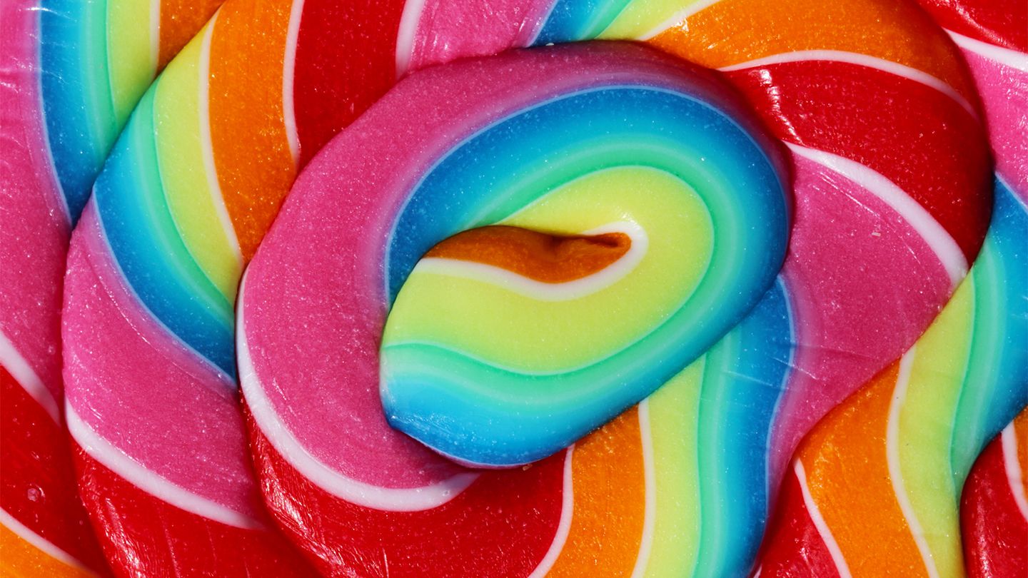 Vibrant rainbow swirl lollipop with glossy candy layers in pink, blue, green, orange, and red.