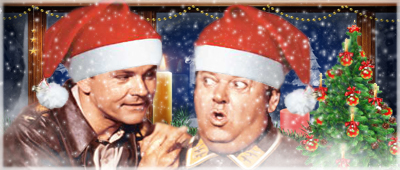 Two men in Santa hats reacting with surprise and amusement beside a lit Christmas tree and snowy window.