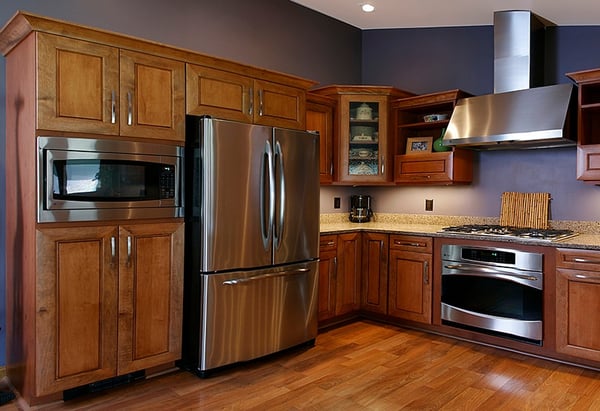 Modern kitchen with stainless steel appliances, wood cabinetry, granite countertops, and dark blue accent wall.