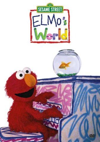 Elmo sits at a colorful desk with a goldfish in a bowl, from "Elmo's World" on Sesame Street.