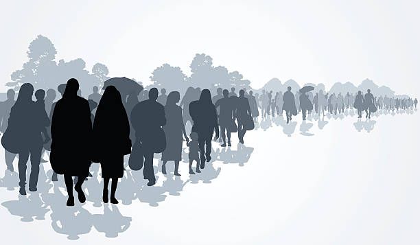 Silhouetted crowd walking in a line across a misty landscape with trees and umbrellas in the background.