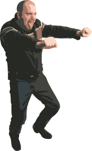 A bald man in a black jacket and jeans striking a dynamic martial arts pose with focused expression.
