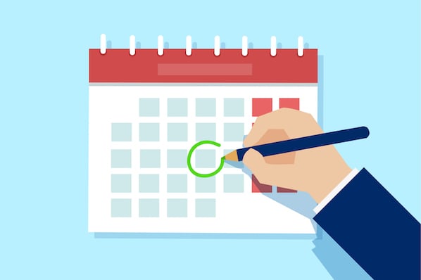 Hand circling a date on a desk calendar with green marker, symbolizing scheduling or appointment confirmation.