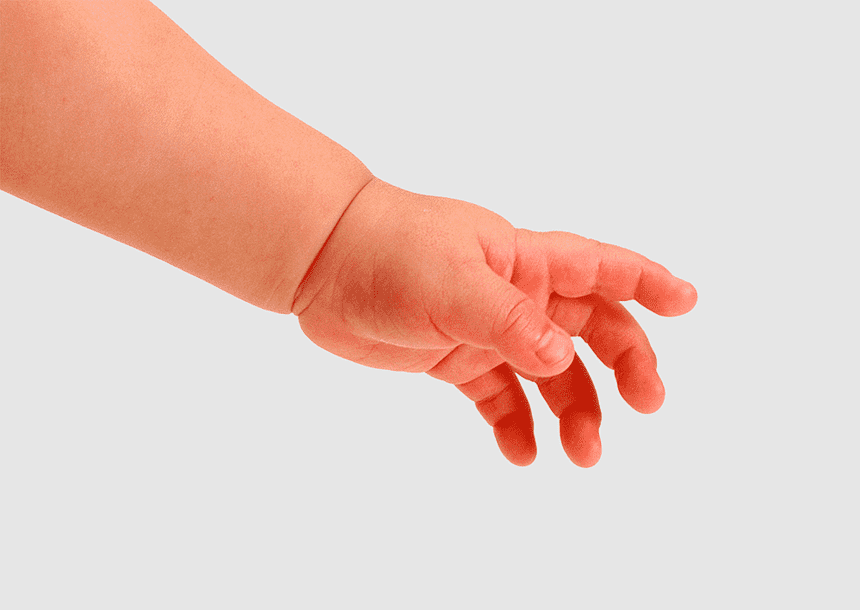 A baby’s small hand reaching out, fingers slightly curled, against a soft gray background.
