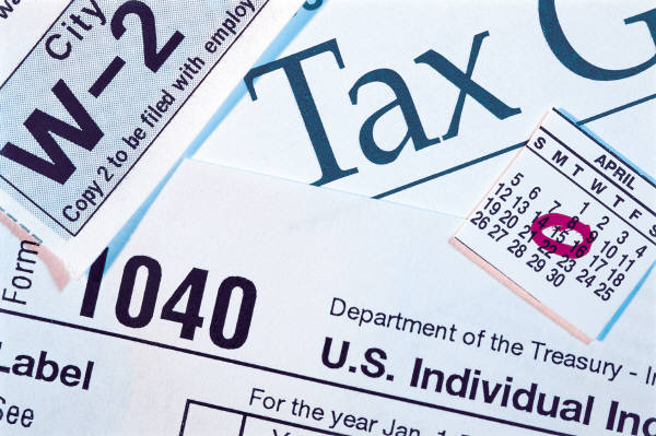 Close-up of U.S. tax forms including W-2, 1040, and calendar highlighting April 15 tax deadline.
