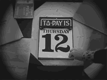 Black-and-white vintage calendar showing "TA-DAY IS THURSDAY 12" with a hand turning the page.
