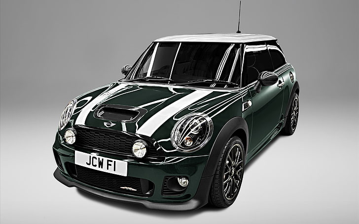 Dark green Mini Cooper with white racing stripes, black wheels, and UK plate JCW F1 on studio gray background.