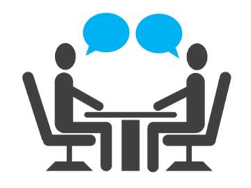 Two stylized figures seated at a table with blue speech bubbles, symbolizing conversation or consultation.