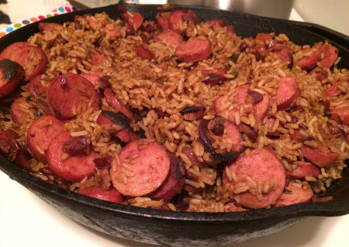 Skillet of jambalaya with rice, smoked sausage slices, and red beans in a cast-iron pan.