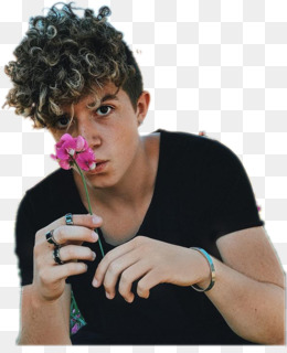 Young man with curly hair holding a pink flower near his face, wearing black shirt and rings.