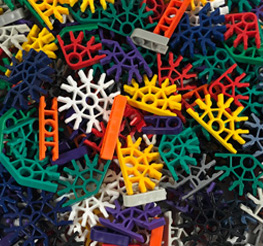 Colorful plastic construction toy pieces including gears, rods, and connectors scattered in a pile.