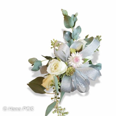 Elegant wrist corsage with white roses, silver ribbon, eucalyptus, and delicate filler blooms on a white background.