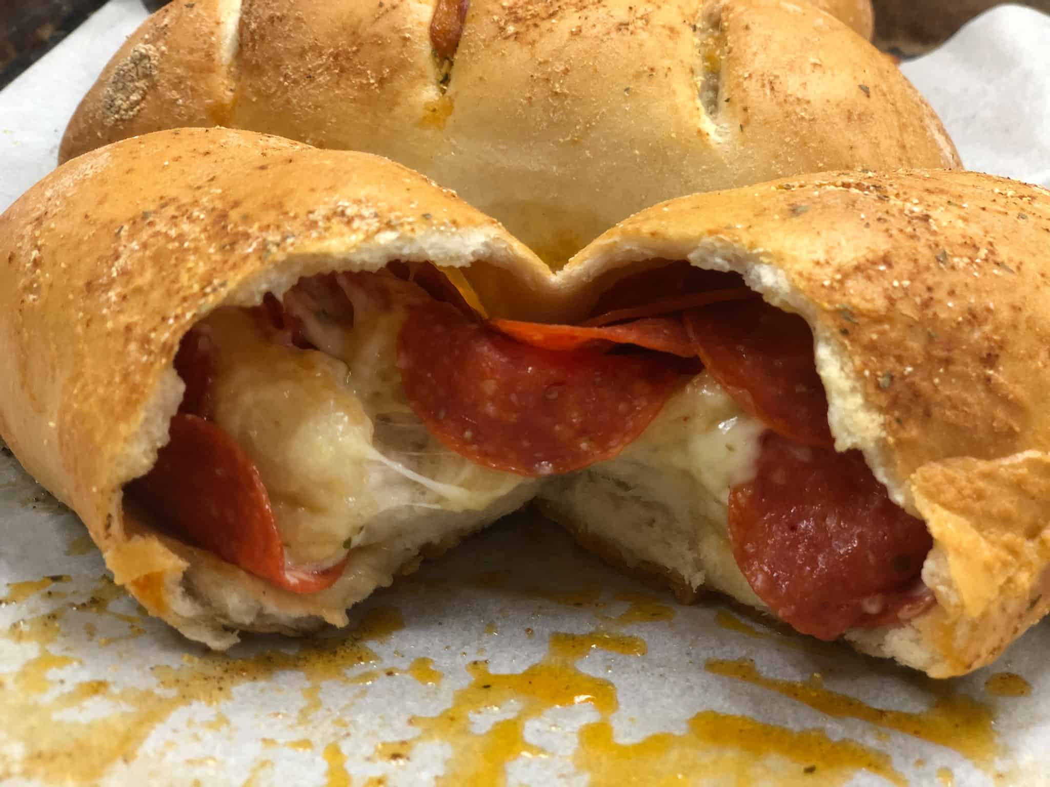 A freshly baked pepperoni-stuffed bread roll, split open to reveal melted cheese and savory pepperoni slices inside.