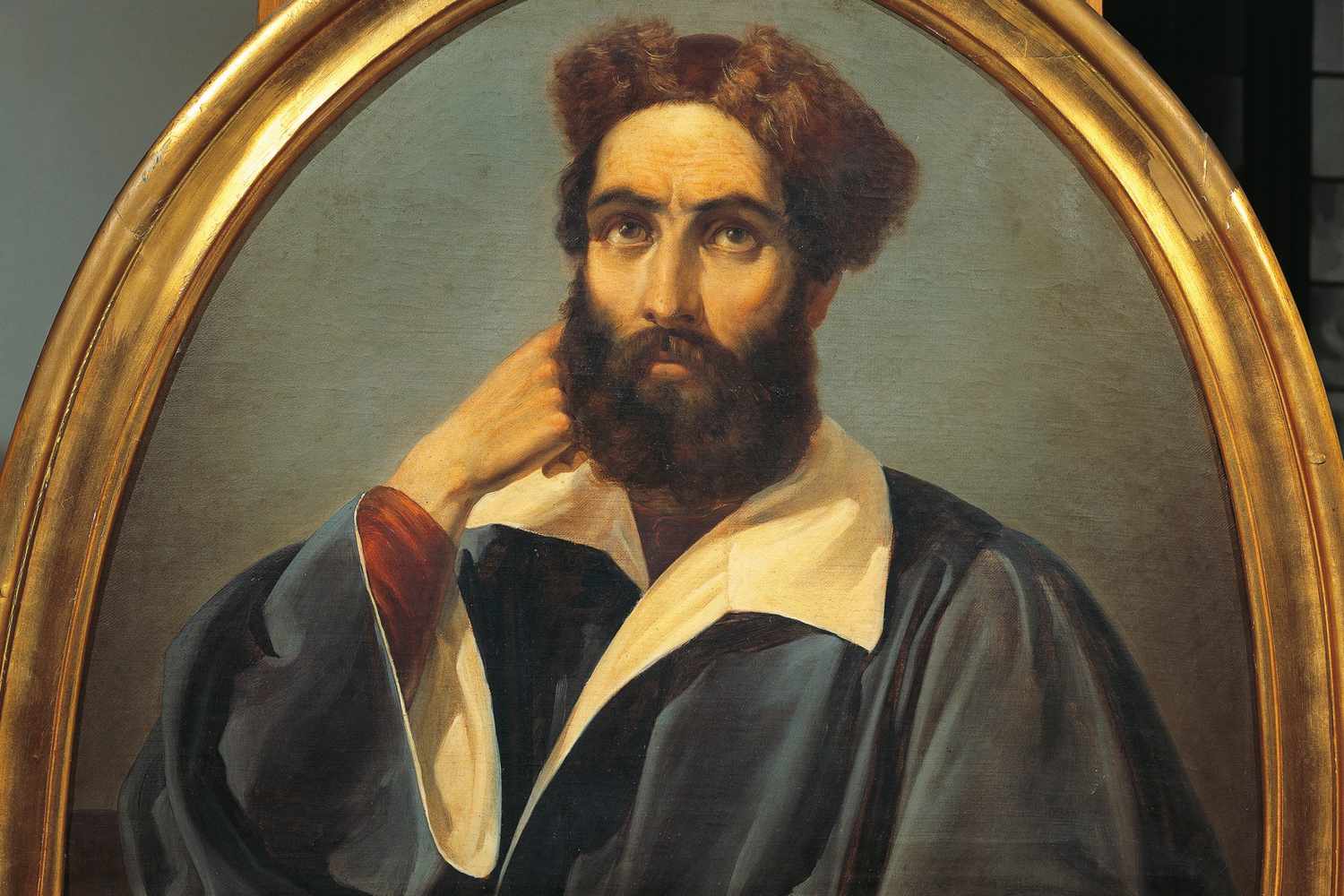 Portrait of a bearded man in Renaissance-style attire, hand resting on chin, within an ornate gold oval frame.
