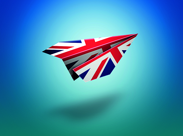 A paper airplane decorated with the UK flag flying against a blue-to-teal gradient background.