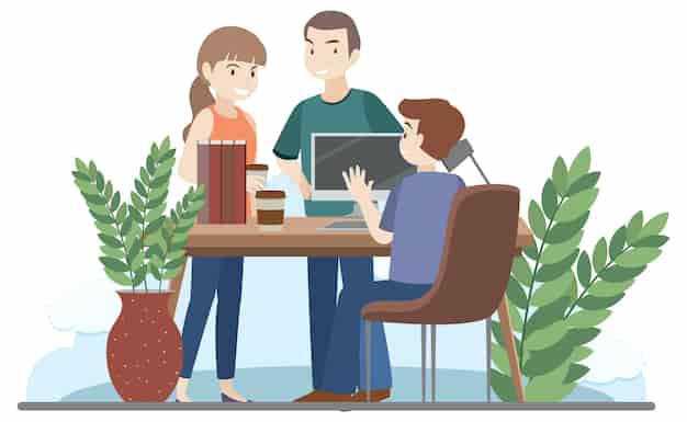 Three professionals collaborating around a desk with laptop, books, and plants in a bright office setting.