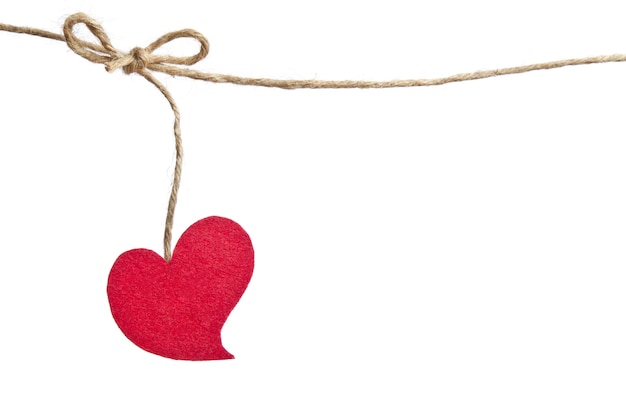 A red felt heart hangs from a rustic twine knot against a white background.