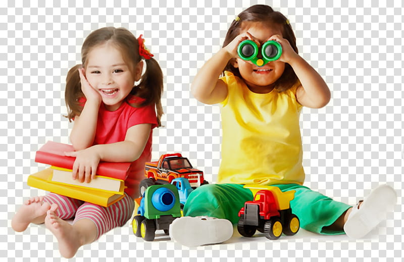 Two smiling girls playing with toys and books; one holds binoculars, the other rests on stacked books.