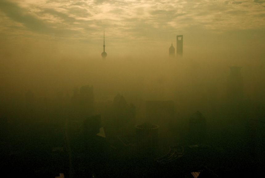 Shanghai skyline shrouded in thick yellow haze, with Oriental Pearl Tower and skyscrapers barely visible through pollution.