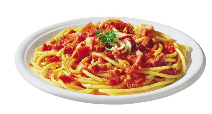 Classic spaghetti alla carbonara with tomato, pancetta, garlic, and parsley on a white plate.