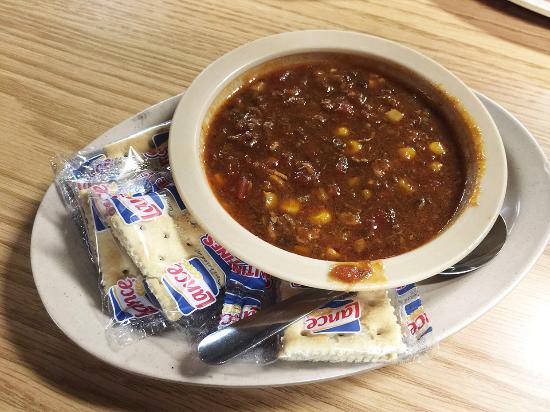 A bowl of hearty chili with corn and beans, served with Lance crackers on a white plate.