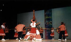 Traditional Filipino dancers performing with bamboo poles and colorful costumes on stage.