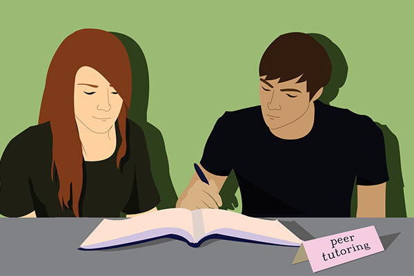 Two students engaged in peer tutoring, studying together at a table with an open book and a "peer tutoring" sign.