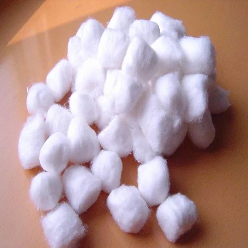 A pile of white cotton balls on a warm-toned wooden surface, soft and fluffy in texture.