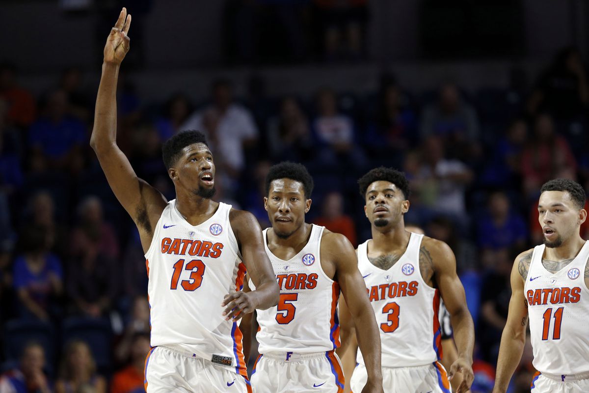 Florida Gators basketball players celebrate during a game, player #13 raising two fingers in victory gesture.