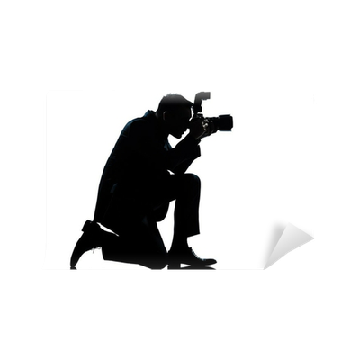 Silhouette of a photographer kneeling and capturing a shot with a DSLR camera against a white background.