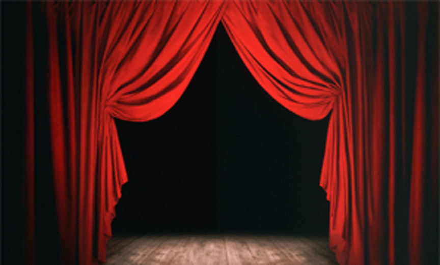 Red stage curtains parted to reveal a dark theater stage with spotlight on wooden floor.