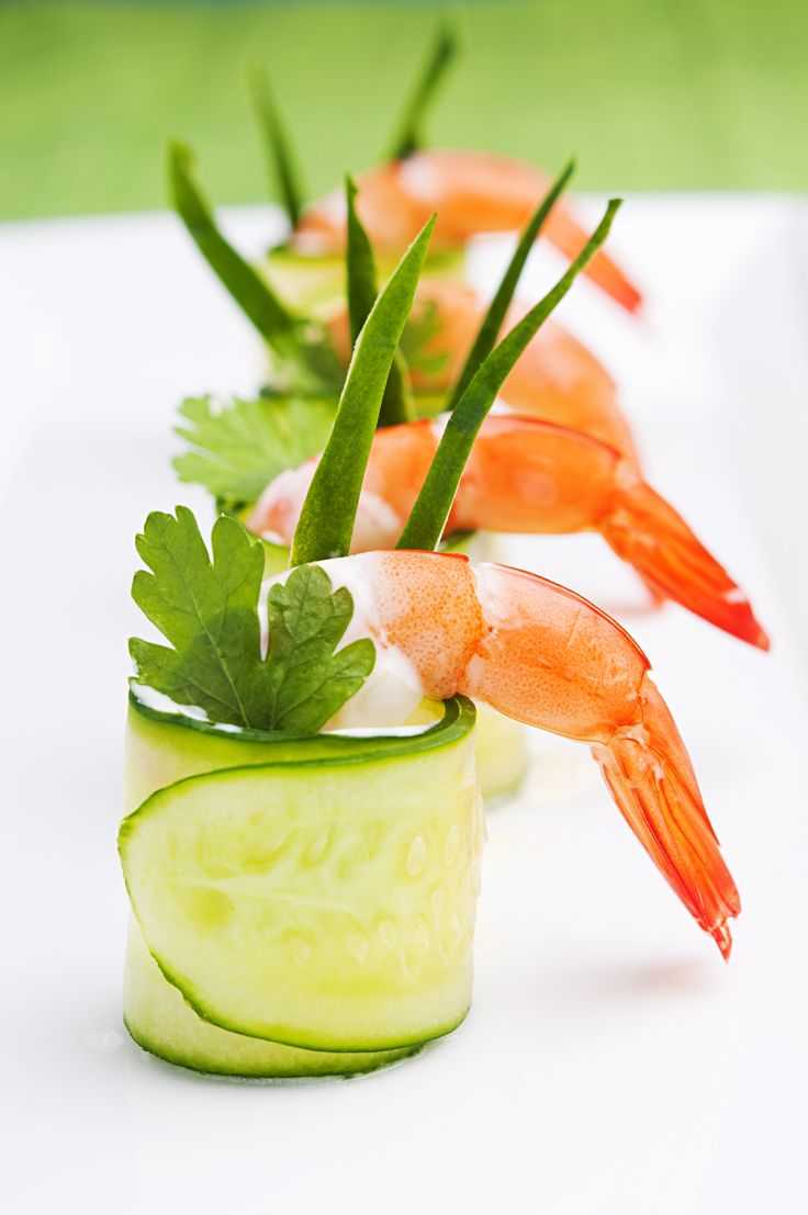 Cucumber rolls with shrimp, parsley, and chives on a white plate, garnished elegantly.