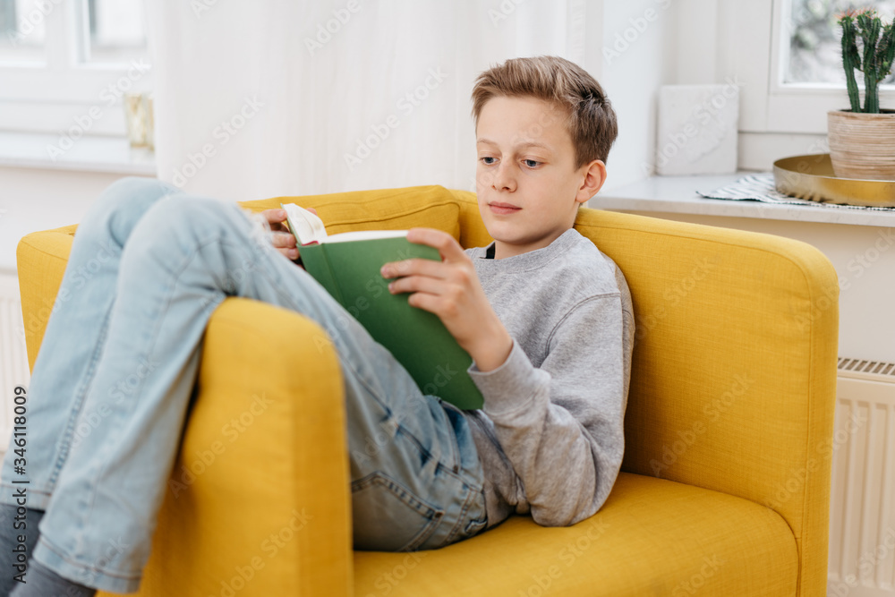 Young boy relaxing at home reading a book Stock-Foto | Adobe Stock